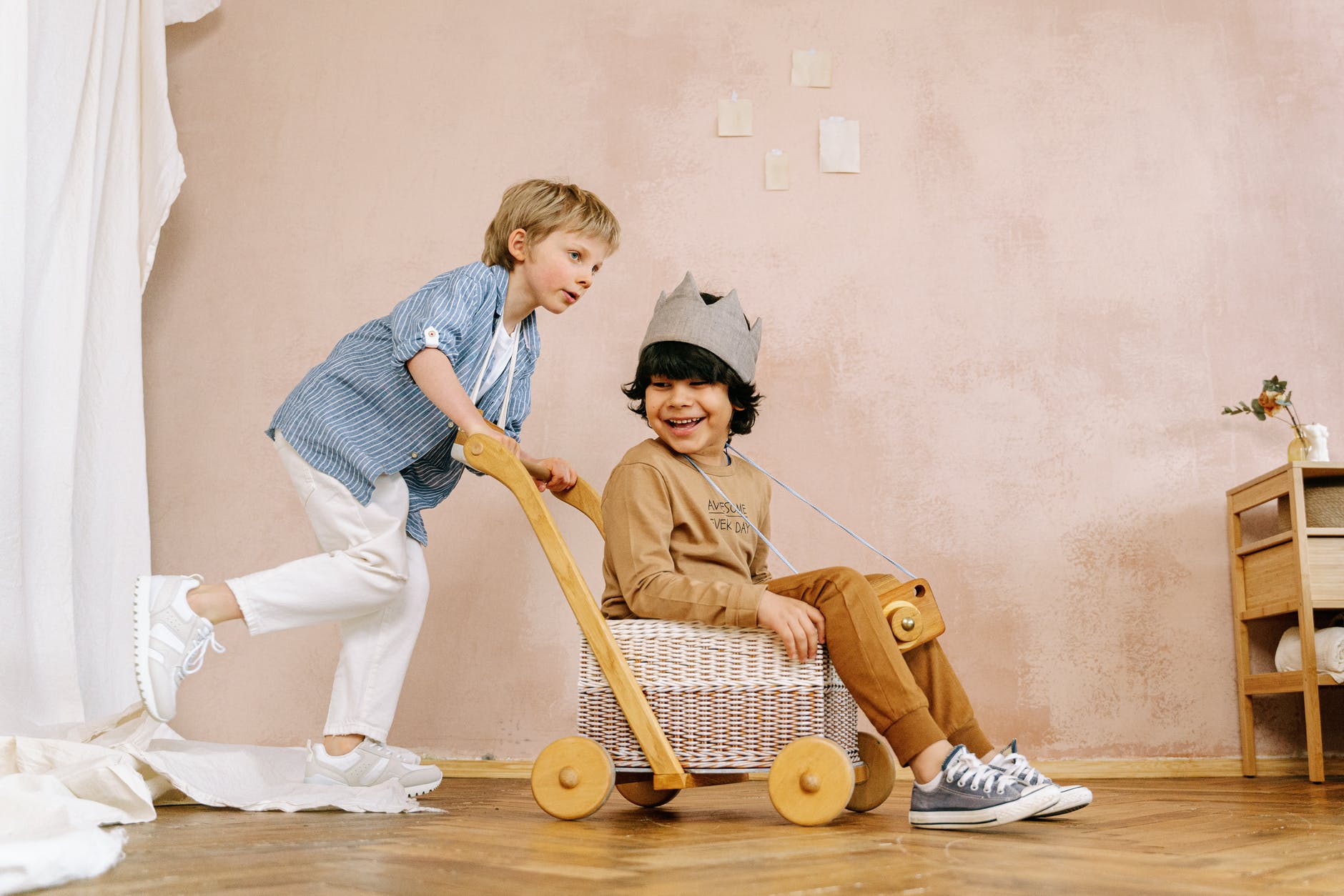 boy pushing a cart with another boy sitting on wicker basket